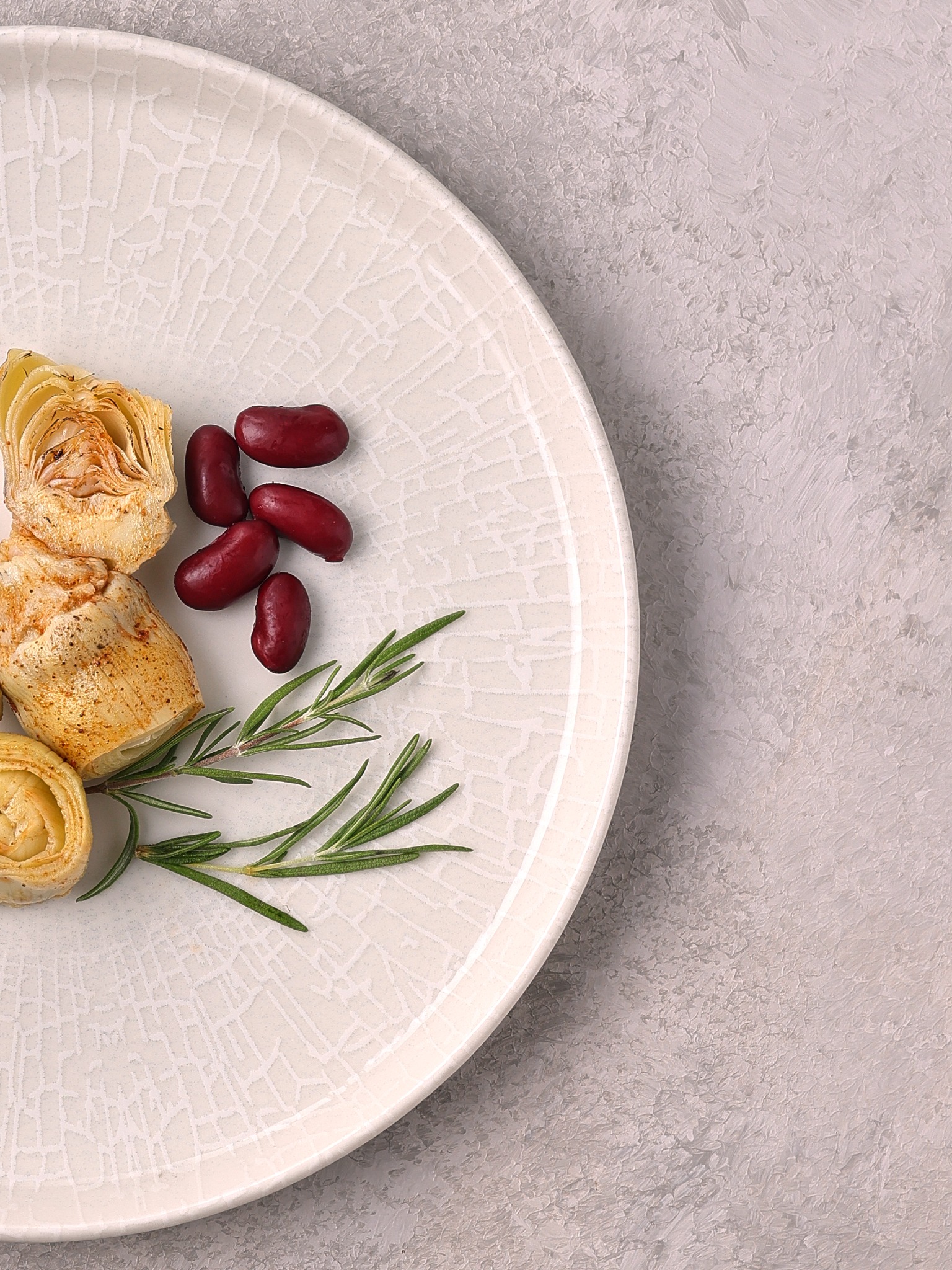 Minimal artichoke and rosemary plating on white crackle plate – fine-dining food styling in Atlanta.