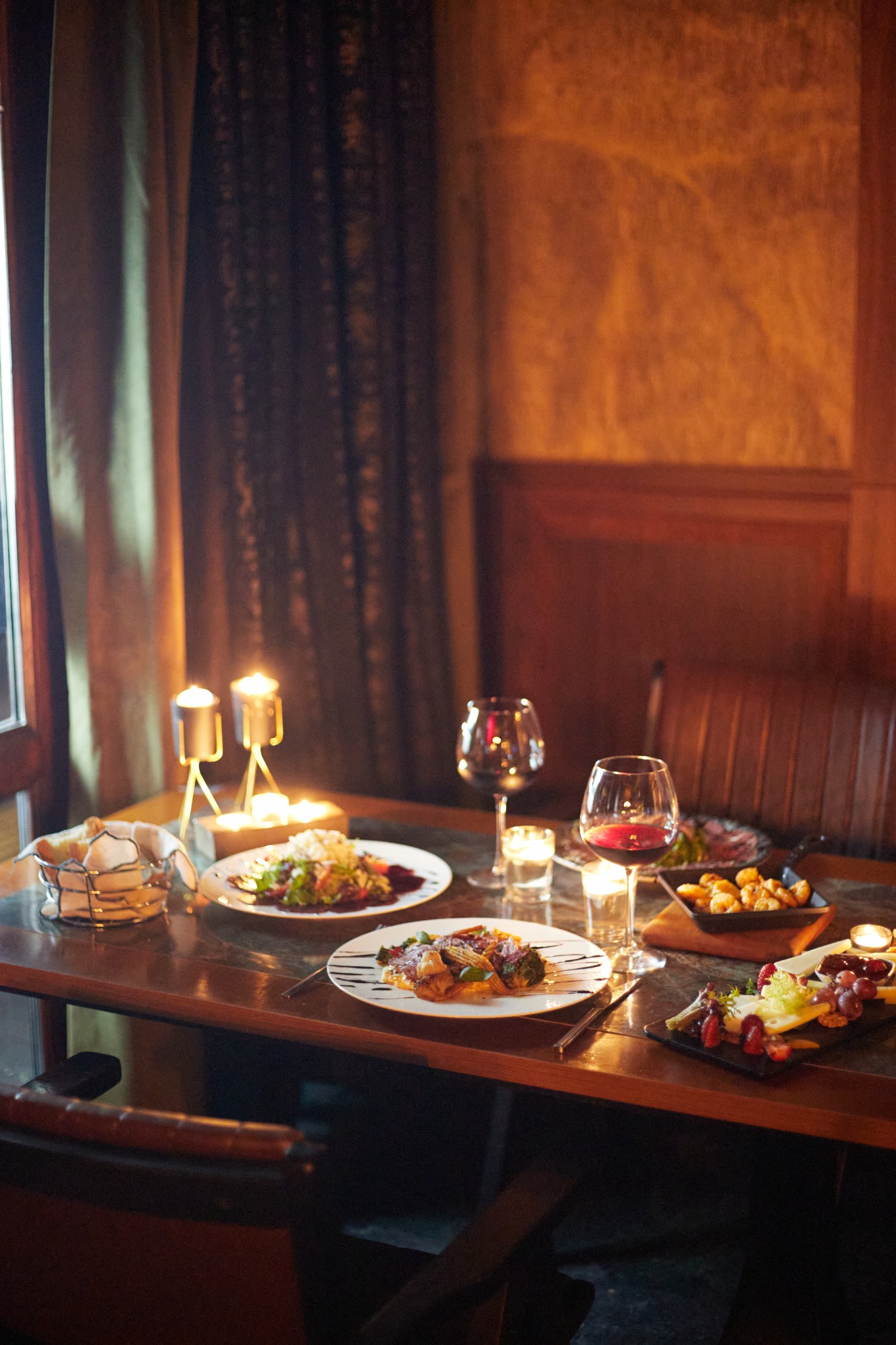 Cozy dining nook with salads, shrimp and red wine under candlelight – Alpharetta hospitality photography.