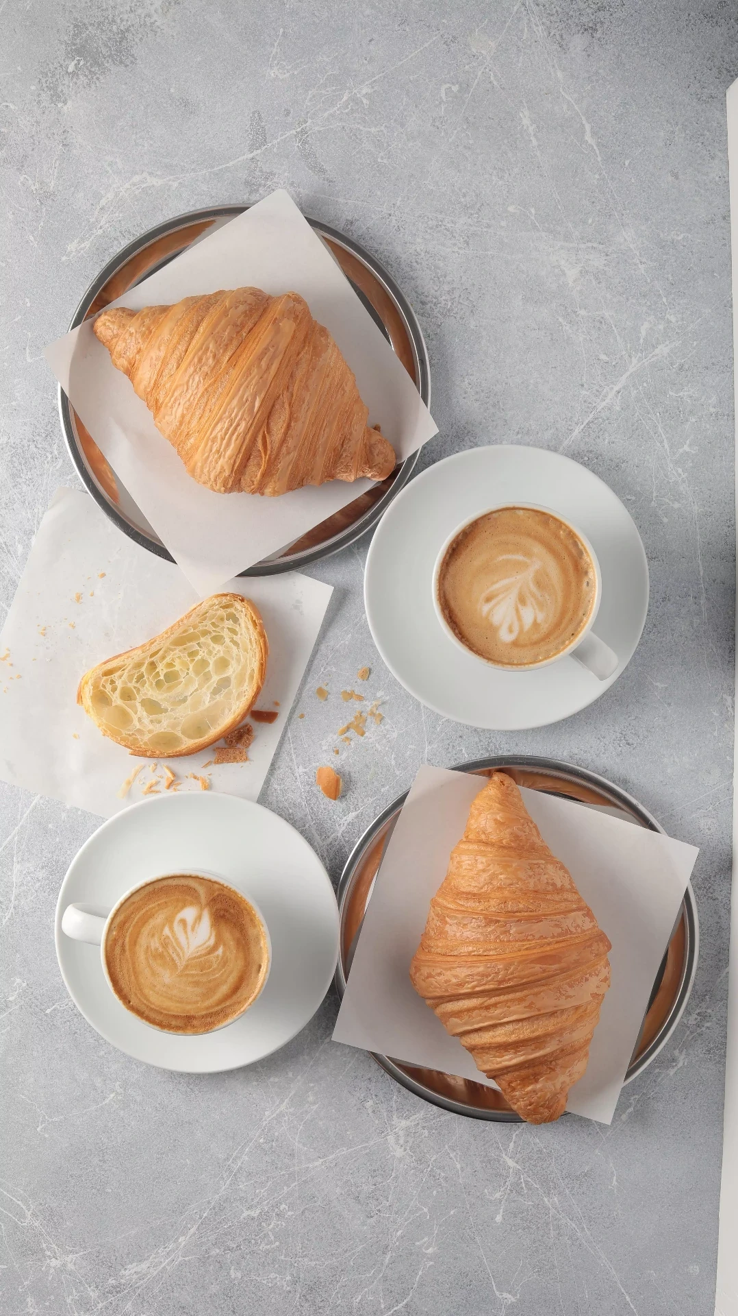 Top-down cappuccinos with buttery croissants on stone backdrop – Atlanta bakery photography.