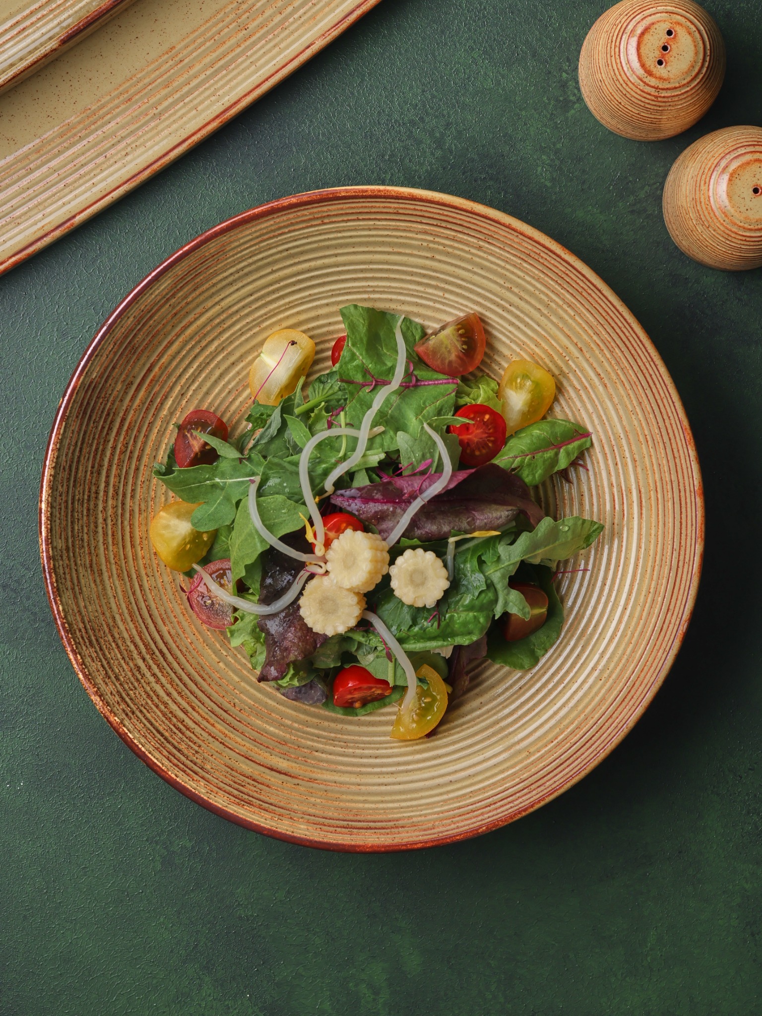 Fresh green salad with cherry tomatoes on rustic amber plate – Atlanta menu photography.