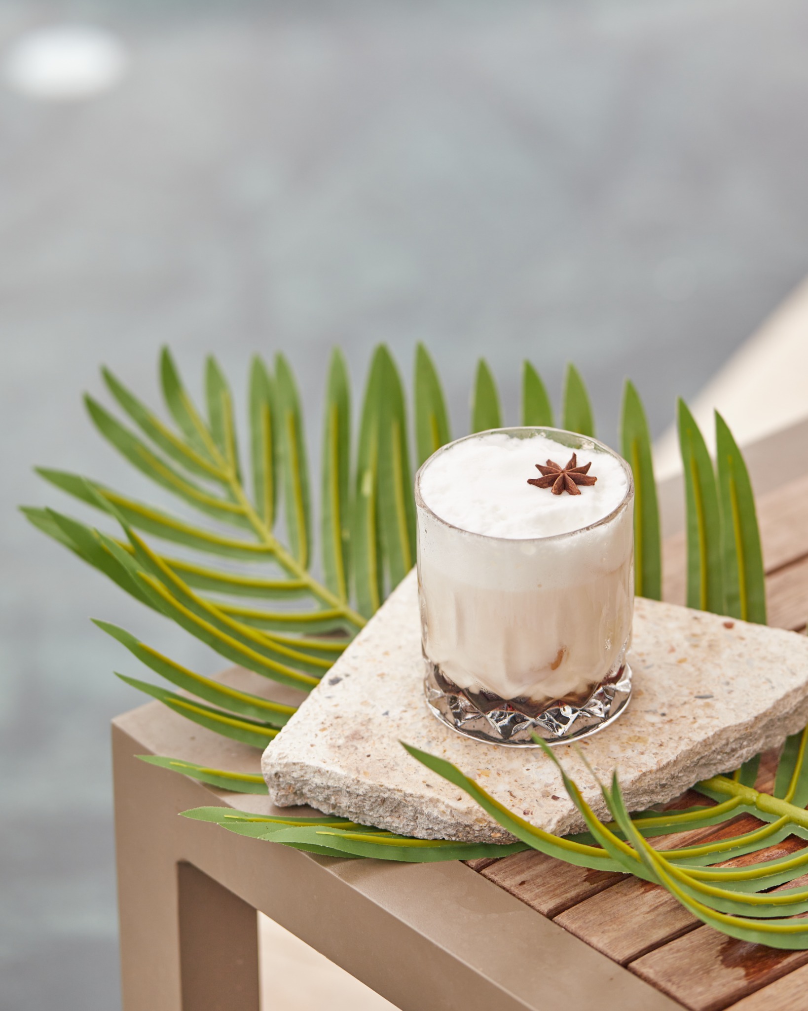 Spiced cream cocktail with star anise on palm leaves – Atlanta drink styling.