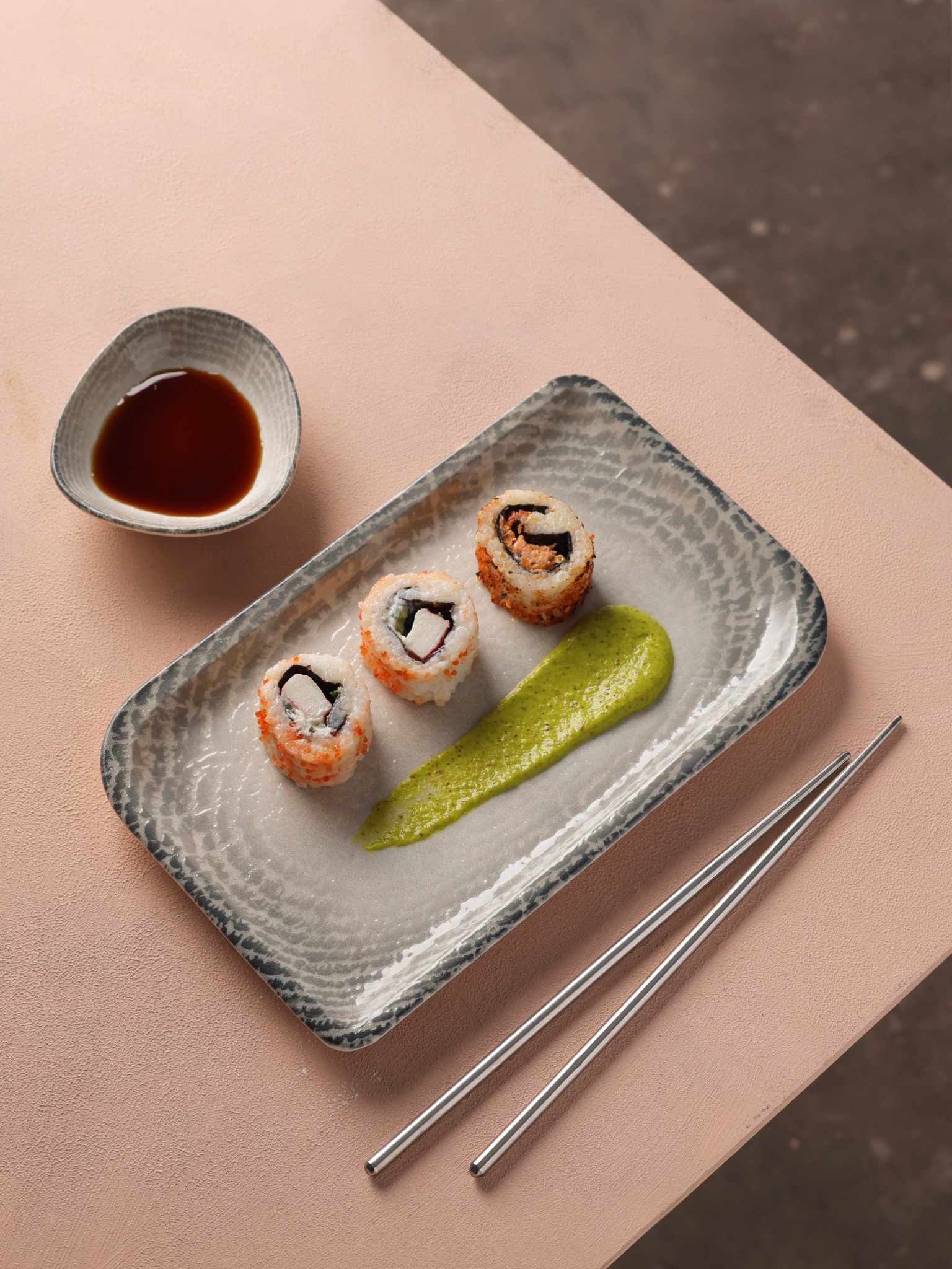 Sushi rolls with green puree and soy sauce on blush surface – Atlanta food photographer.