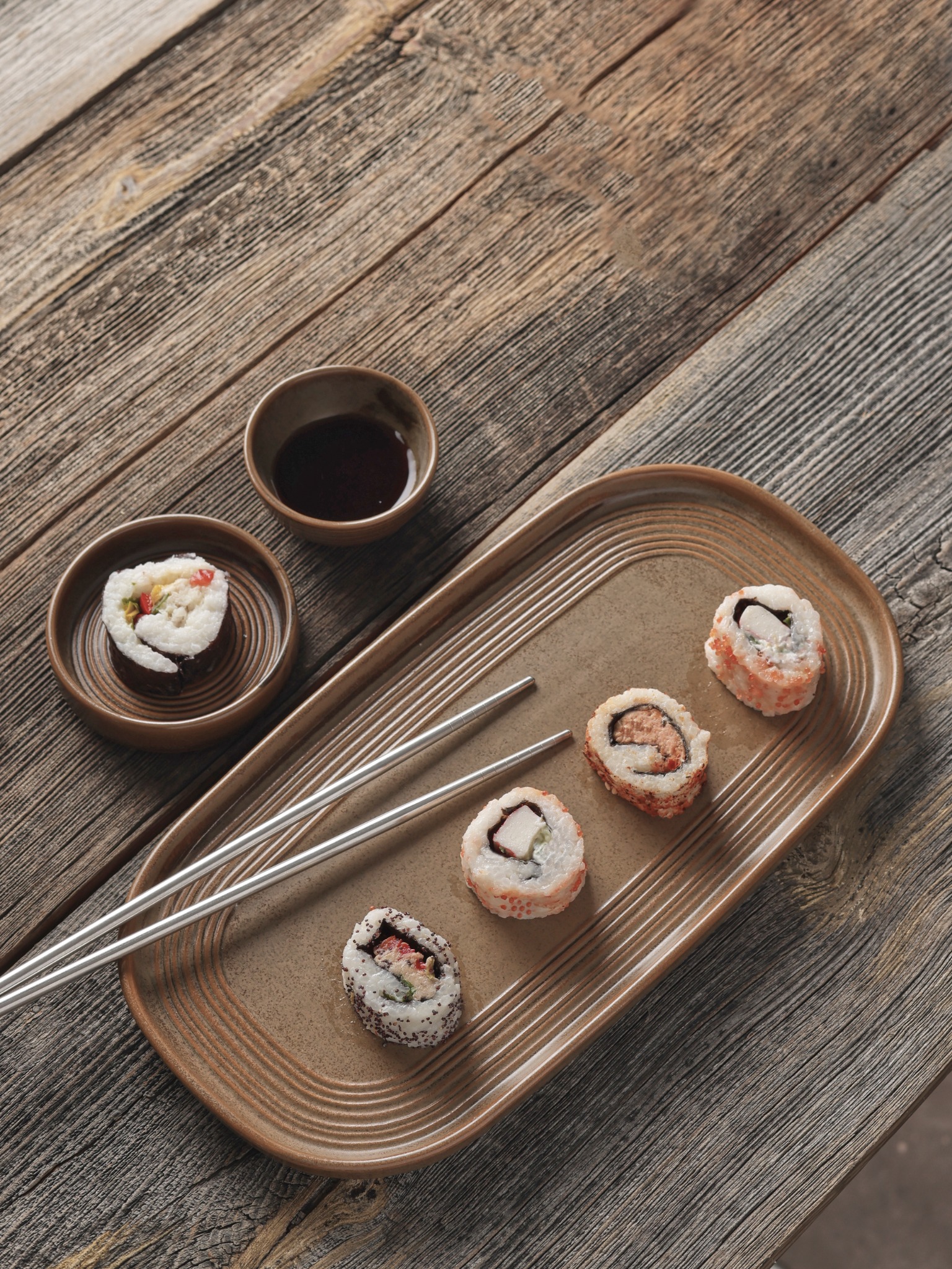 Sushi rolls on rustic wood board with steel chopsticks – Atlanta food photography.
